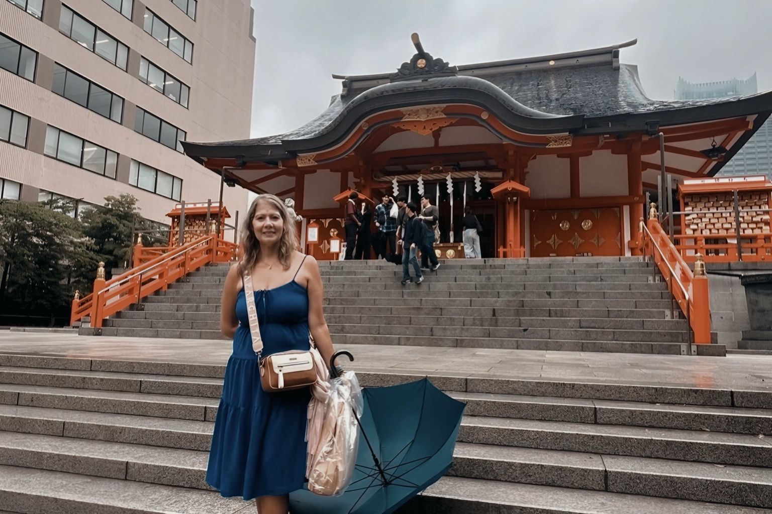 Viajera de JAPAN360 frente al santuario, con vestido azul y paraguas. Ver reviews.